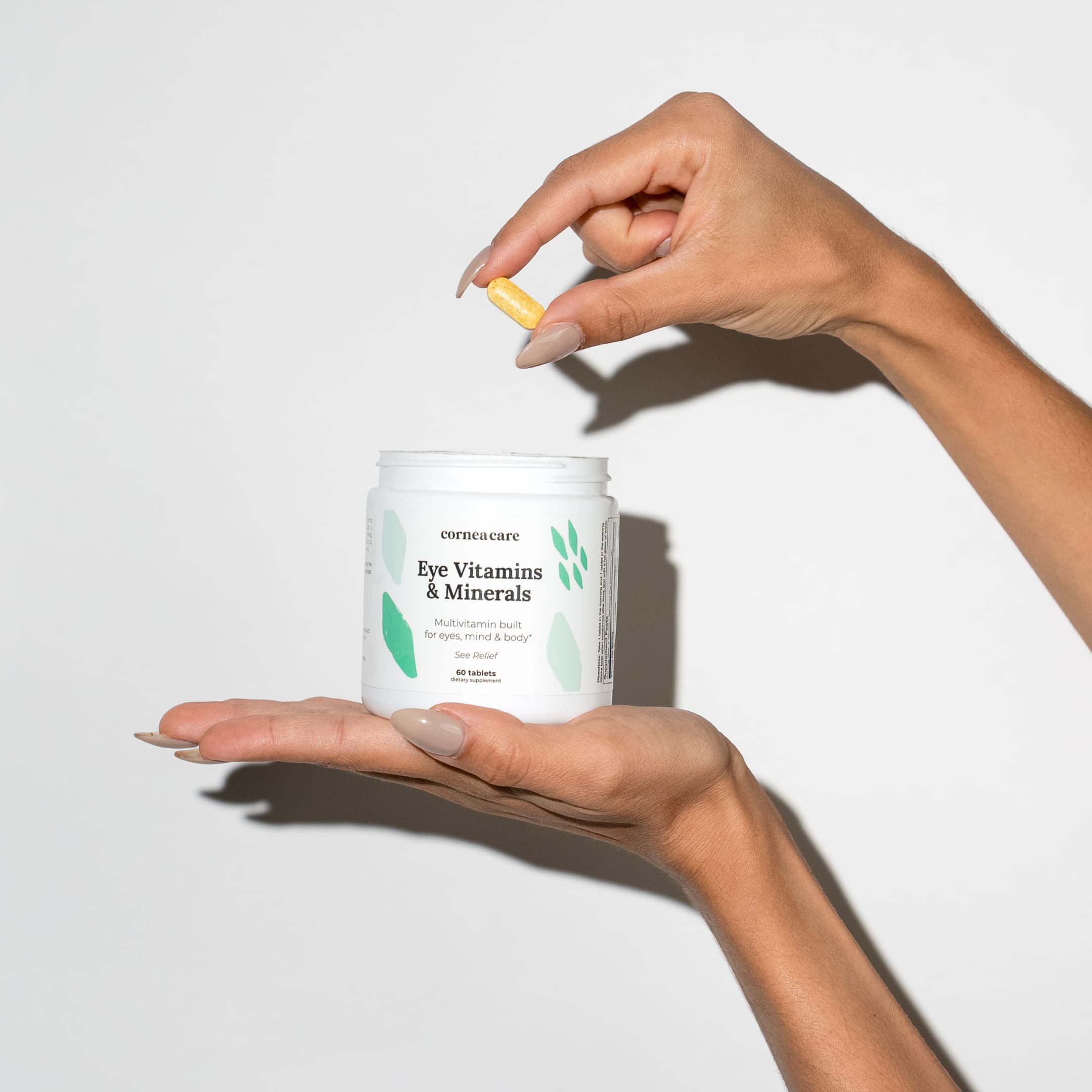 CorneaCare Eye Vitamins and Minerals Hand holding bottle and multivitamin